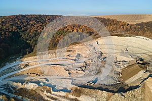 Aerial view of open pit mine of sandstone materials for construction industry with excavators and dump trucks. Heavy