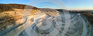 Aerial view of open pit mine of sandstone materials for construction industry with excavators and dump trucks. Heavy