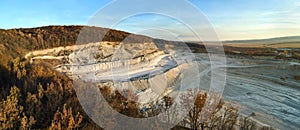 Aerial view of open pit mine of sandstone materials for construction industry with excavators and dump trucks. Heavy