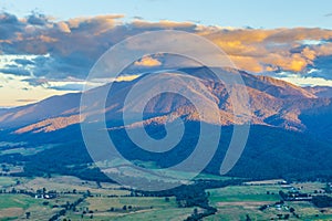 Aerial view of orange sunset light on beautiful mountain in Australian Alps.