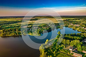 Aerial view of Ostrovno lakes, green fields and trees, small villages, summer at sunset, Belarus, Europe