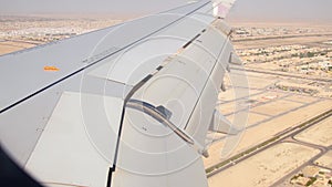 Aerial view over Abu dhabi city suburbs and desert with wings background window. Deserted landscape of UAE and plane wing view