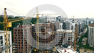 Aerial view over the big construction of a neighborhood of high-rise buildings. Construction cranes and unfinished