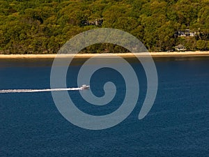 Aerial view over the calm waters with a sailboat traveling in Oyster Bay near Lloyd Harbor, New York