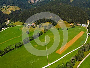 Aerial view over green meadow in Zgornje Jezersko, to Kamnik-Savinja Alps on a sunny summer day in Slovenia. Travel and tourism