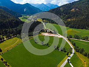 Aerial view over green meadow in Zgornje Jezersko, to Kamnik-Savinja Alps on a sunny summer day in Slovenia. Travel and tourism