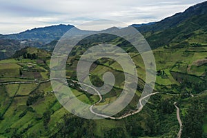 Aerial view over a green valley with a road meandering through the meadows in the Andes of Ecuador