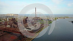 Aerial view over industrialized city with air atmosphere and river water pollution from metallurgical plant near sea