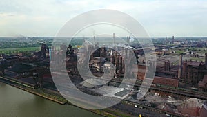 Aerial view over industrialized city with air atmosphere and river water pollution from metallurgical plant near sea