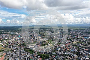 Aerial view over a large city with a beautiful cloudscape and in green covered hills in the background