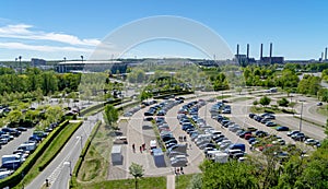 Aerial view over a large parking lot with many parked cars onto a football stadium and the Volkswagen factory