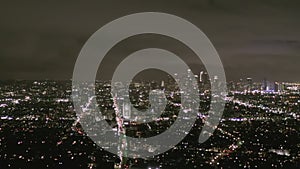 Aerial: view over Los Angeles at night with Wilshire boulevard glowing streets and city car traffic lights