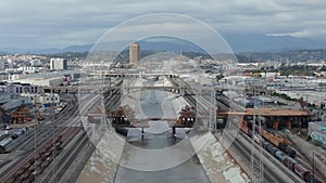 Aerial: view over Los Angeles river bridge being built under construction site with overcast cloudy sky