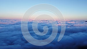 Aerial view over the mountains with sea of fog during morning sunrise in blue sky. Sea of clouds around mountain peaks at sunrise