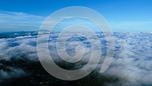 Aerial view over the mountains with sea of fog during morning sunrise in blue sky. Sea of clouds around mountain peaks at sunrise