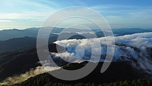 Aerial view over the mountains with sea of fog during morning sunrise in blue sky. Sea of clouds around mountain peaks at sunrise