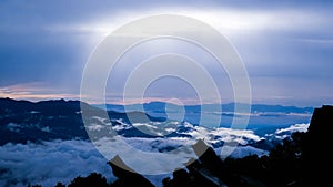 Aerial view over the mountains with sea of fog during morning sunrise in blue sky. Sea of clouds around mountain peaks at sunrise