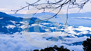 Aerial view over the mountains with sea of fog during morning sunrise in blue sky. Sea of clouds around mountain peaks at sunrise