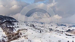Aerial view over winter in the mountain village from Romania ,winter storm with low clouds and mist