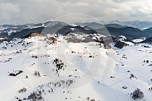 Aerial view over winter in the mountain village from Romania ,winter storm with low clouds and mist