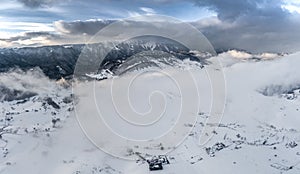 Aerial view over winter in the mountain village from Romania ,winter storm with low clouds and mist