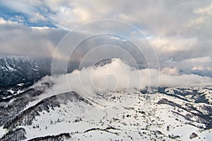 Aerial view over winter in the mountain village from Romania ,winter storm with low clouds and mist