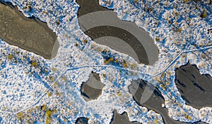 Aerial view over winterly snow and ice-clad peat bog landscape in natural Estonian