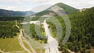 Aerial view overhead of street down curvy mountain road through green forest valley, Top view of countryside road