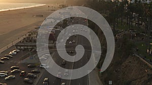 AERIAL: View of Pacific Coast Highway PCH next to Santa Monica Pier, Los Angeles with light traffic and ocean view by at