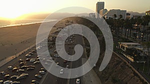 AERIAL: View of Pacific Coast Highway PCH next to Santa Monica Pier, Los Angeles with light traffic and ocean view by at