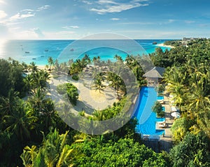 Aerial view of palms, pool, bungalow, sandy beach, blue sea photo