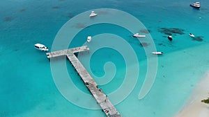 Aerial view of paradise Maldives tropical beach with pier and speed boats on island. Summer and travel vacation concept.