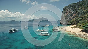 Aerial view of paradise vacation on passenger boats. Tourists rest at sand beach of Palawan island