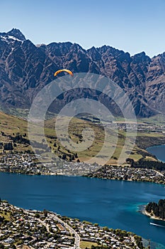 Aerial view of a paraglider over Queenstown, New Zealand with Lake Wakatipu under a blue sky