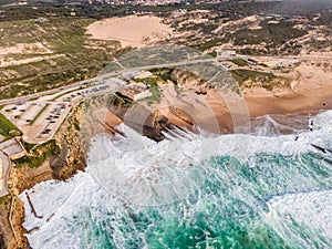 Aerial view of a parking lot and an endless road along the wild coastline in southern Portugal, view of Guincho beach and the