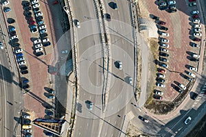 Aerial view of parking lot with parked cars and asphalt bridge road with traffic, top view from drone