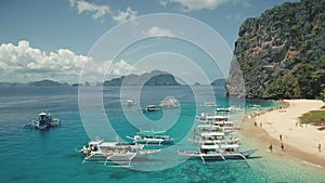Aerial view of passenger boats with tourists rest at sea sand beach of Palawan island, Philippines