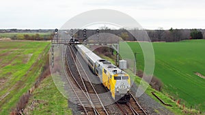 Aerial view of a passenger train approaching in a rural setting