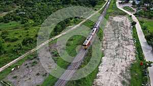 Aerial view of a passenger train traveling on the tracks in the countryside on a sunny day.