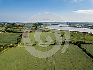 Aerial view of a patchwork of farm fields in the Suffolk countryside with the River Deben in the distance