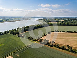 Aerial view of a patchwork of farm fields in the Suffolk countryside with the River Deben in the distance