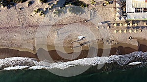 Aerial view of a peaceful beach with gentle waves lapping the shore, dotted with beachgoers. Costa Del Sol, Marbella