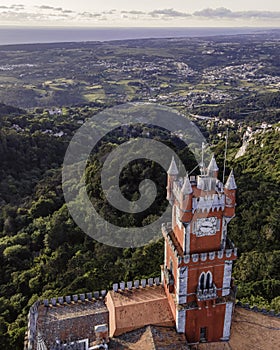 Aerial view of Pena Castle clock tower with forest in background, view of the Romanticist castle on hilltop, Sintra, Lisbon, photo