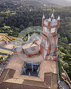 Aerial view of Pena Castle clock tower with forest in background, view of the Romanticist castle on hilltop, Sintra, Lisbon,