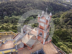 Aerial view of Pena Castle clock tower with forest in background, view of the Romanticist castle on hilltop, Sintra, Lisbon,