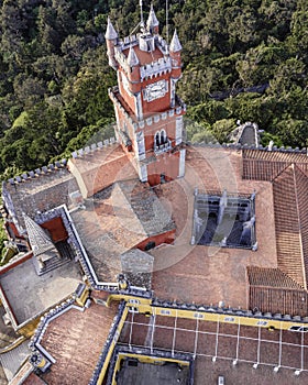 Aerial view of Pena Castle clock tower with forest in background, view of the Romanticist castle on hilltop, Sintra, Lisbon,