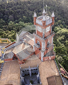 Aerial view of Pena Castle clock tower with forest in background, view of the Romanticist castle on hilltop, Sintra, Lisbon,