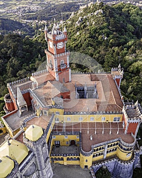 Aerial view of Pena Castle clock tower with forest in background, view of the Romanticist castle on hilltop, Sintra, Lisbon,