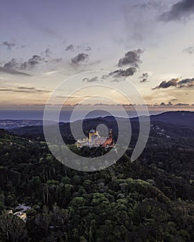 Aerial view of Pena Palace in Sintra, a Romanticist castle on hilltop surrounded by forest during a beautiful sunset, Sintra,