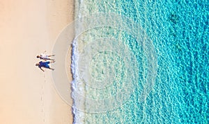 Aerial view of a people couple on the beach on Bali, Indonesia. Vacation and adventure. Beach and turquoise water. Top view from d